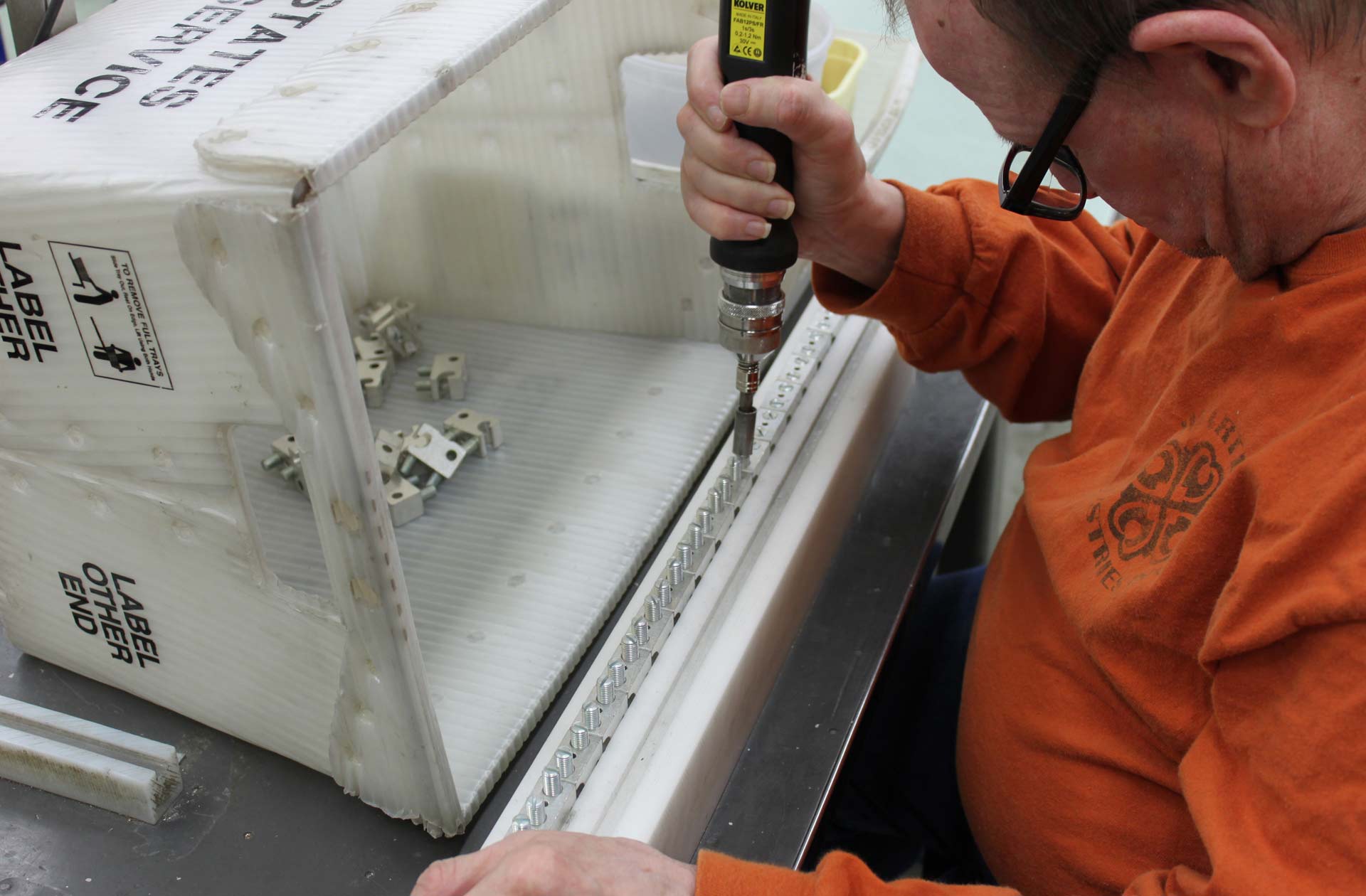 male worker holding a screwdriver and adjusting brackets